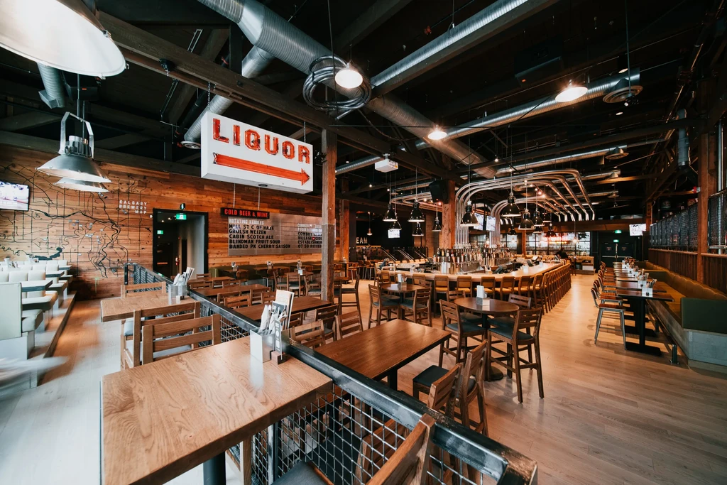 Empty modern bar interior with industrial-rustic decor and liquor sign.