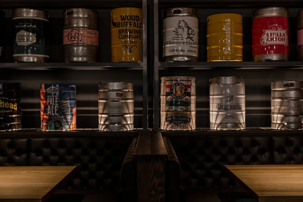 Dimly lit restaurant interior featuring decorative shelves displaying branded beer kegs.