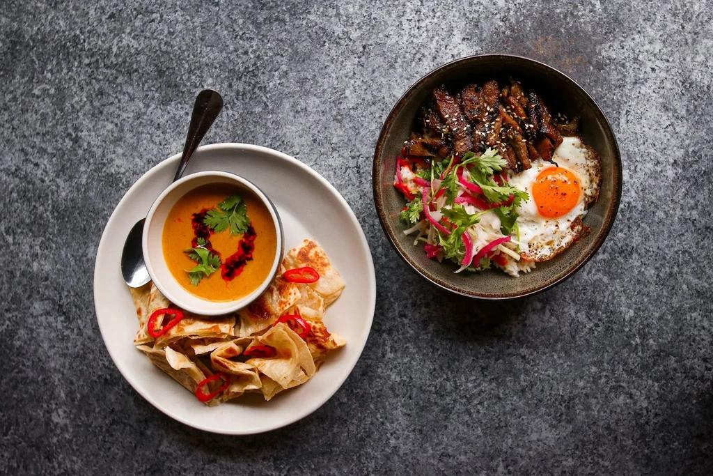 Overhead: Curry with flatbread, grilled meat, salad, and fried egg.