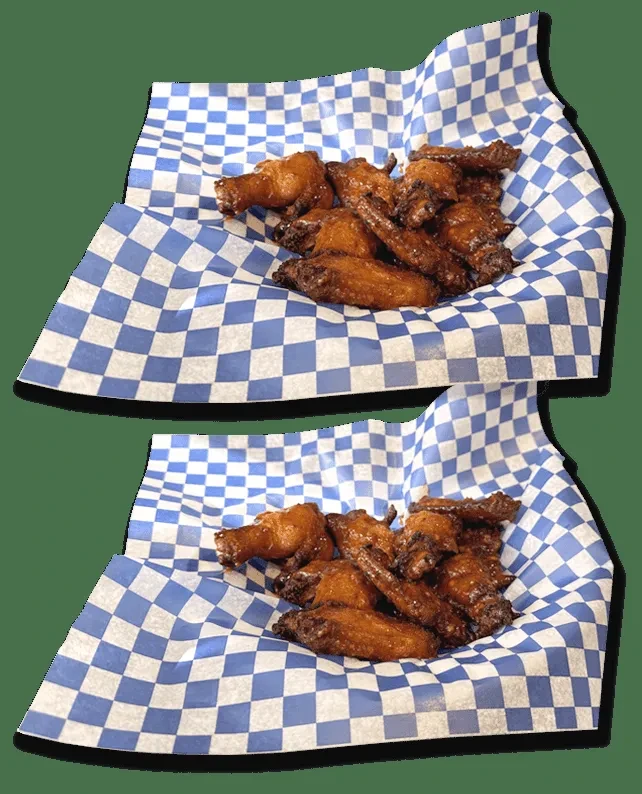 Two portions of dark brown, glossy, crispy chicken wings on deli paper.