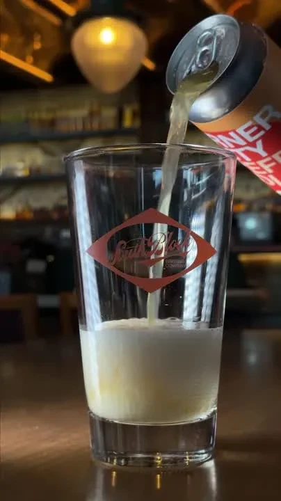 Fizzy beverage from "INNER CITY" can pours into "South Block" glass.