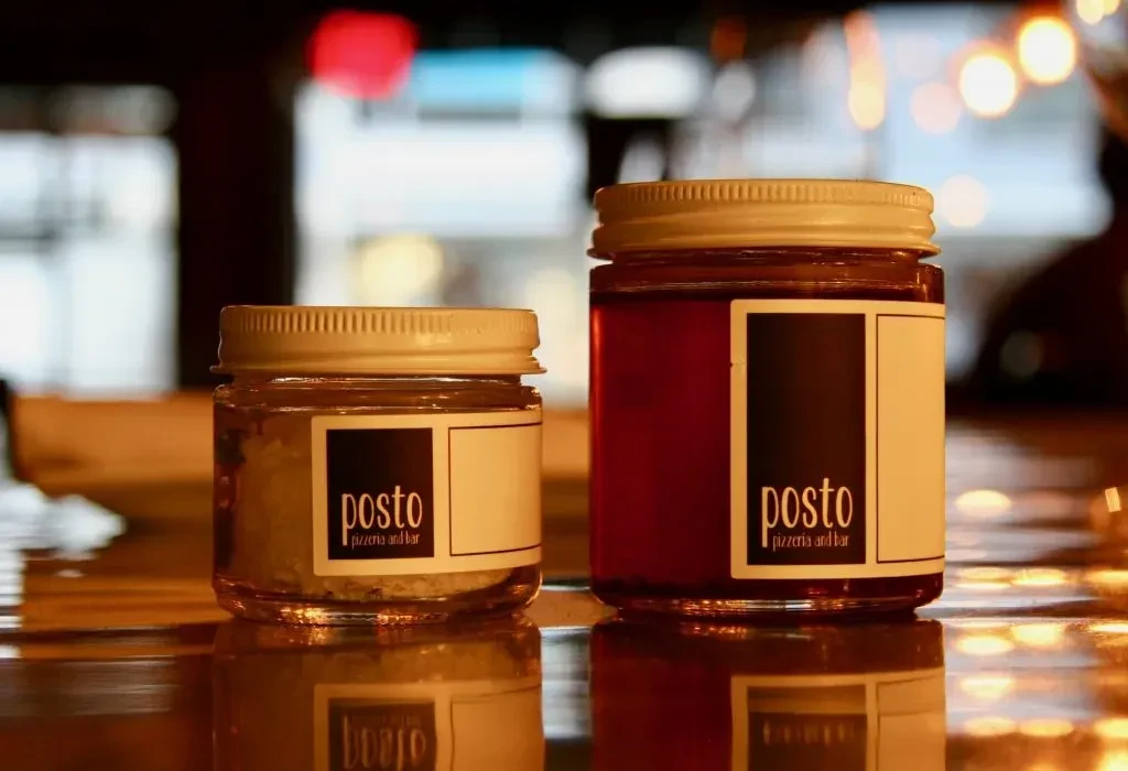 Two 'posto pizzeria and bar' jars with light granules and red liquid.