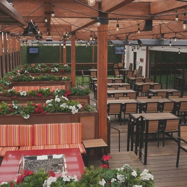 Empty outdoor restaurant patio with tiered planters and string lights.