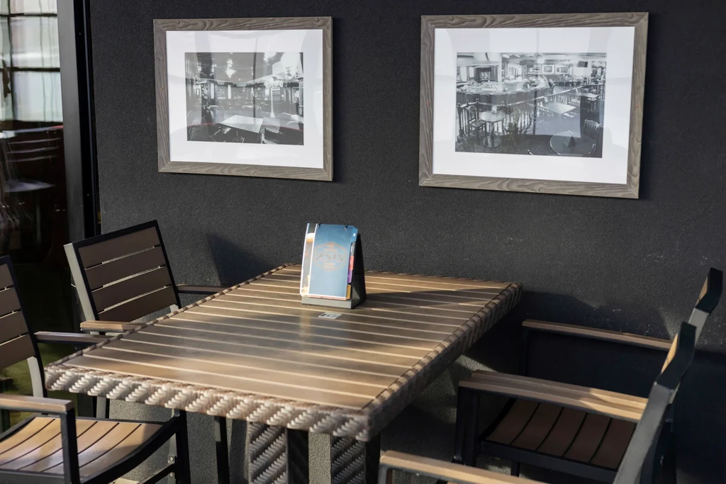 Restaurant corner with slatted table, three chairs, menu, and framed photos.