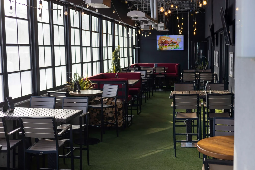 Modern restaurant dining area with red booths, green turf floor, and large windows.