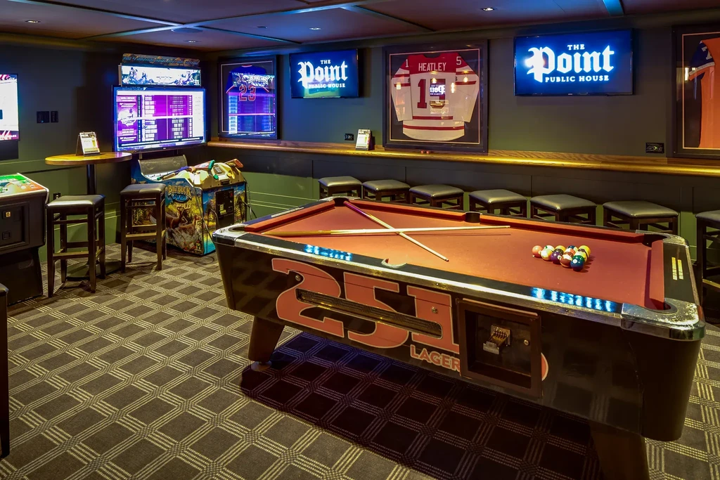 Dimly lit public house game room with pool table and arcade games.