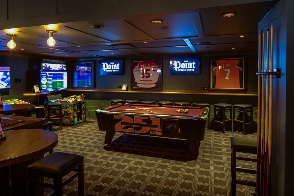 Modern sports bar interior with pool table, arcade games, and sports jerseys.