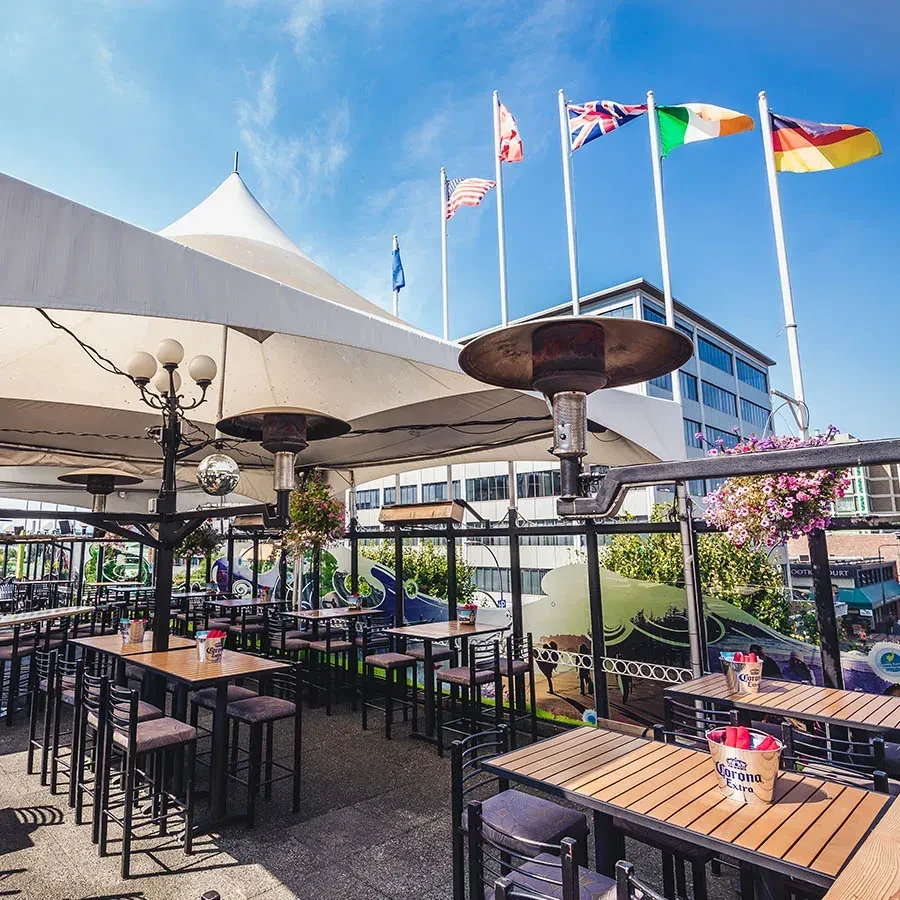 Outdoor dining patio under white canopies, with international flags.