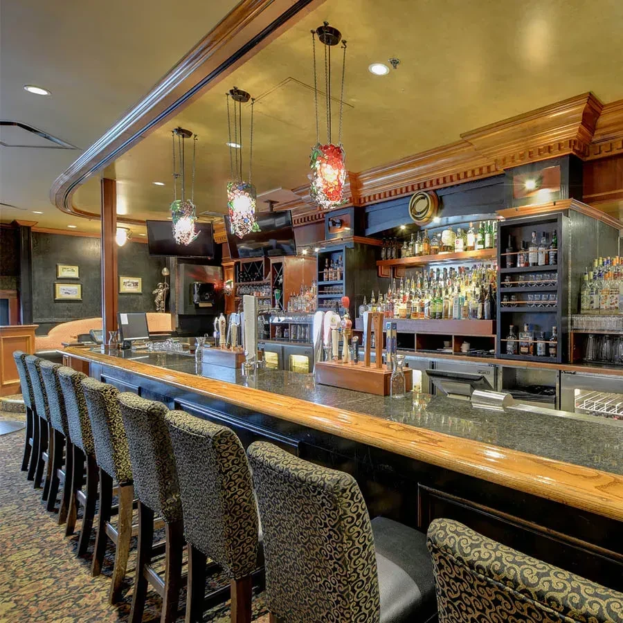 Empty, upscale bar with curved counter, liquor display, and mosaic lights.