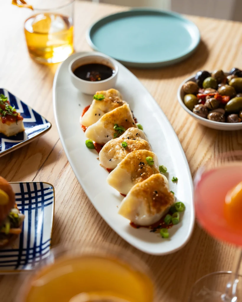 Overhead shot: five crispy pan-fried dumplings on a table with drinks.