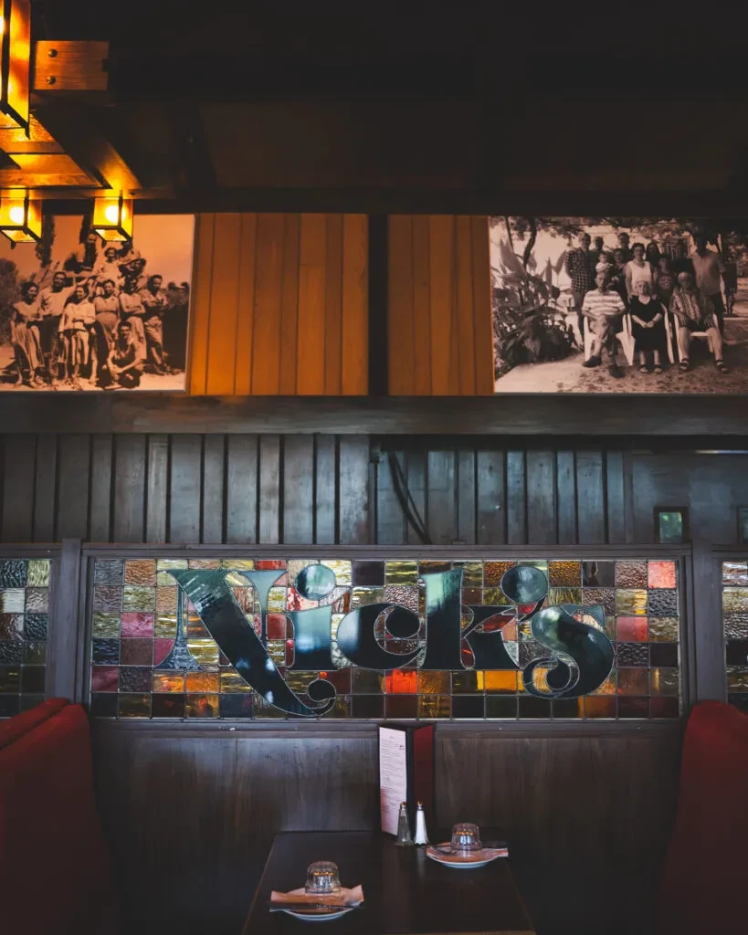 Cozy restaurant dining area with "Nick's" stained glass and historical photos.