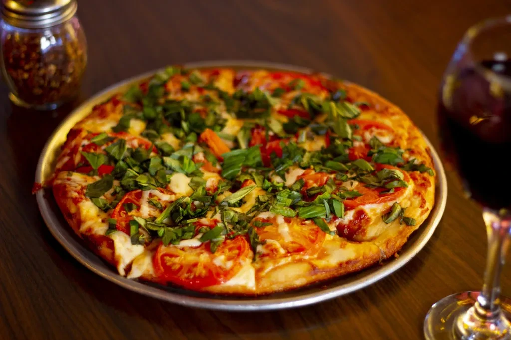 Whole thin-crust pizza with cheese, tomato, basil, and red wine.