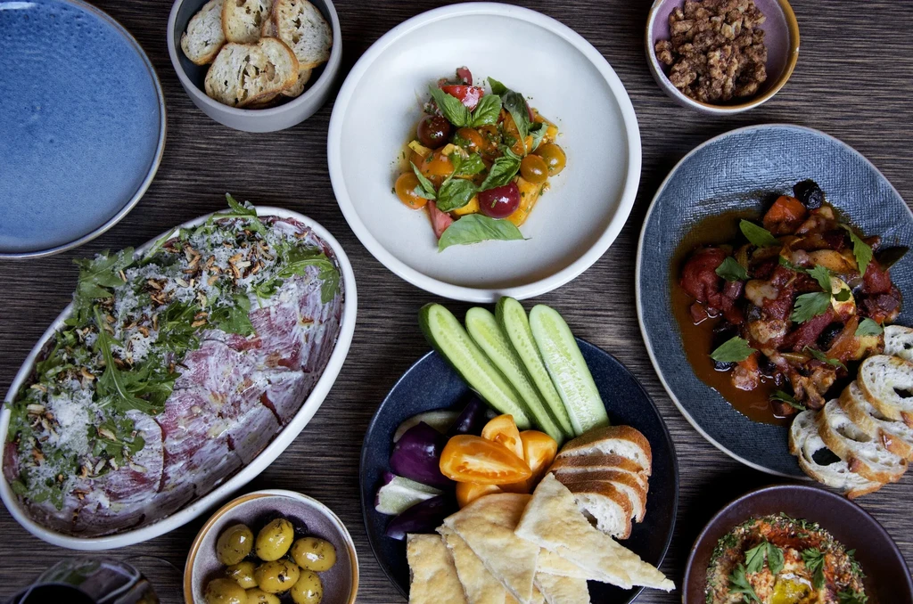 Overhead shot of diverse dishes including salad, stew, and crudités.