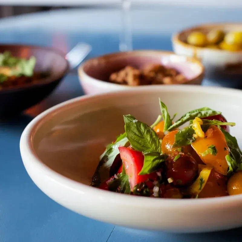 White bowl of vibrant tomato and basil salad.
