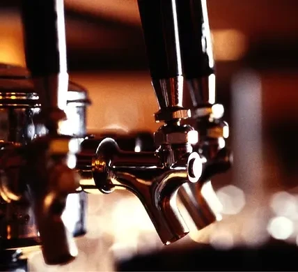 Close-up of three gleaming draft beer taps with dark handles.
