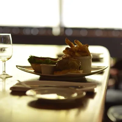 A burger, fries, and water on a polished restaurant table.