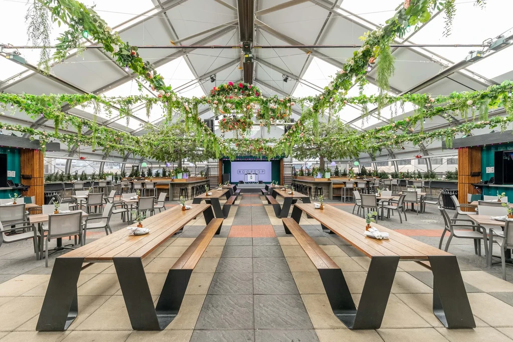 Empty modern rooftop venue with tent ceiling and lush green decor.