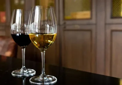Two wine glasses, one red and one white, on a reflective surface.