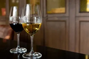 Two wine glasses, one red and one white, on a dark surface.