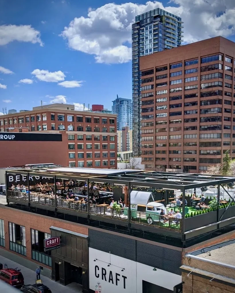 Bustling urban rooftop patio, CRAFT Beer Hall, featuring a camper van.