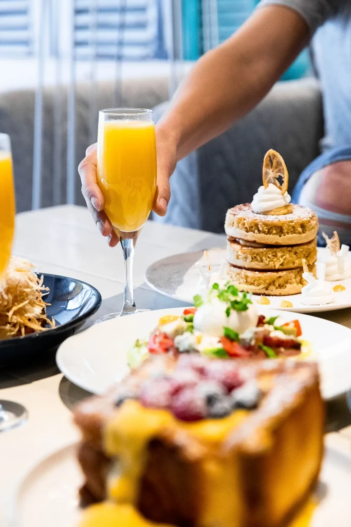 Table of breakfast food: French toast, pancakes, salad, potatoes, and mimosa.