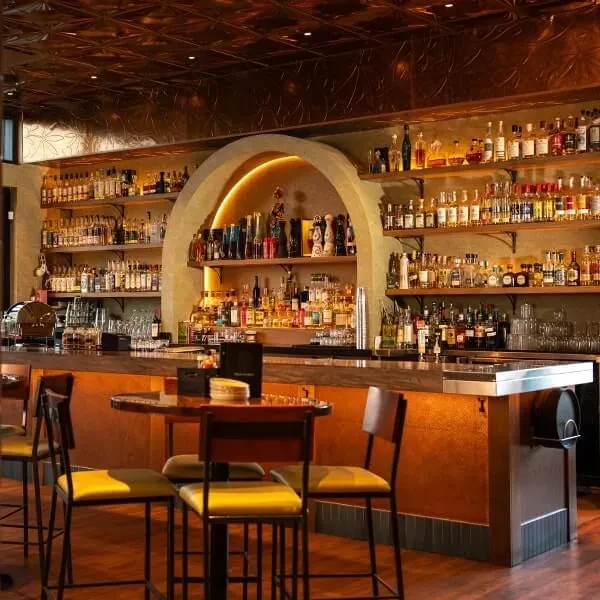 Well-stocked wooden bar counter and seating in a stylish interior.