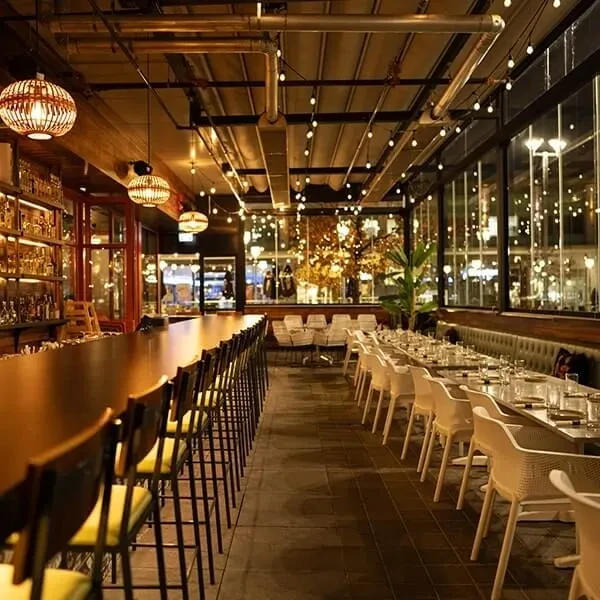 Upscale restaurant bar and dining area with warm lighting and city views.