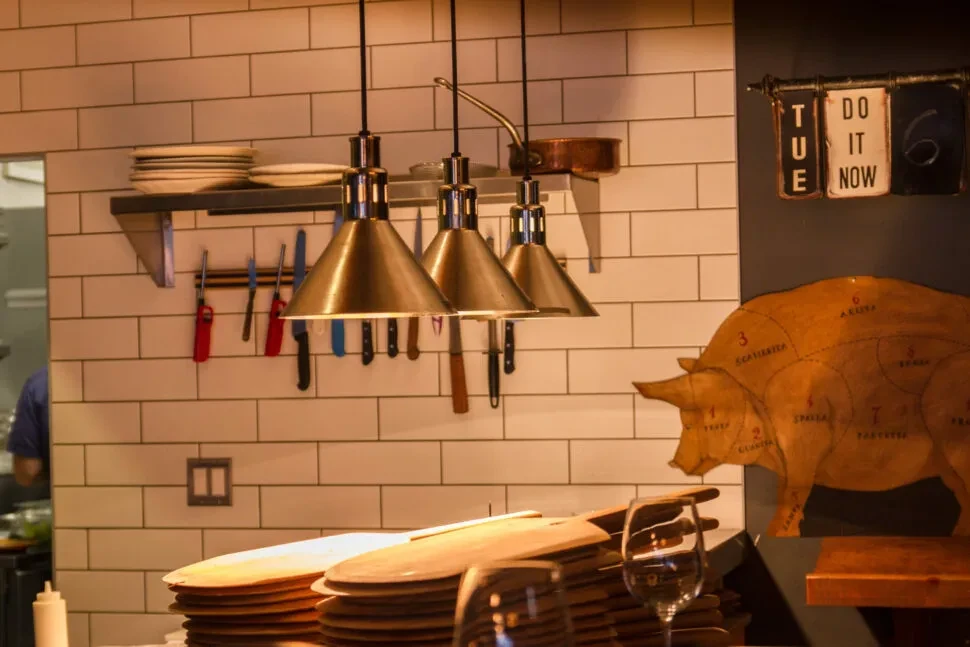 Restaurant counter with kitchenware, modern lights, tiled wall, and pig diagram.