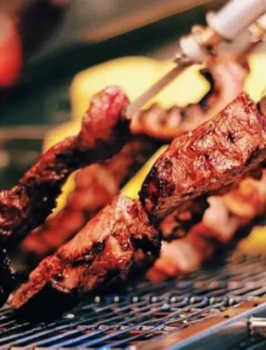 Close-up of dark, caramelized meat skewers on a metal grate.