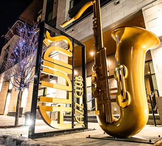 Illuminated "BLUES JAZZ CLUB" sign and giant golden saxophone at night.