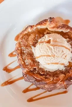 Golden-brown fruit tart with melting ice cream and caramel sauce.