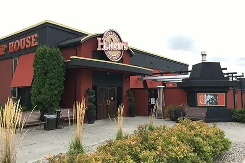 Hudson's Canadian Tap House exterior, red building with landscaping and patio.