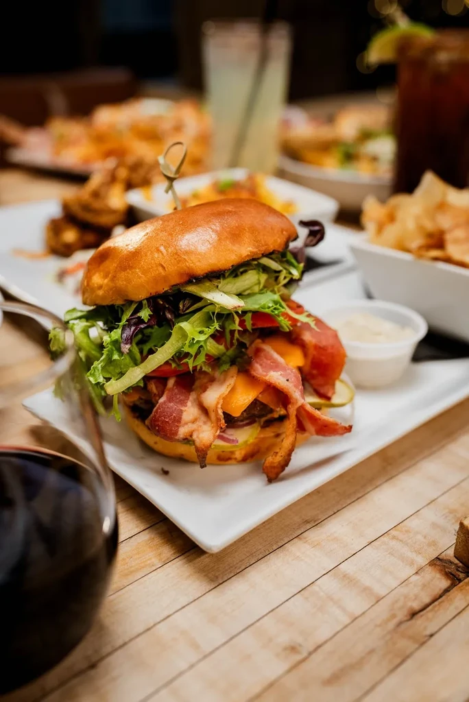 A gourmet bacon cheeseburger with sauce and drinks in a restaurant.