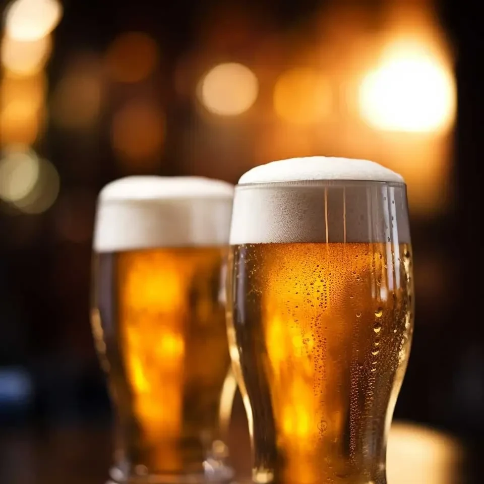 Two glasses of cold golden beer with frothy heads and bokeh background.