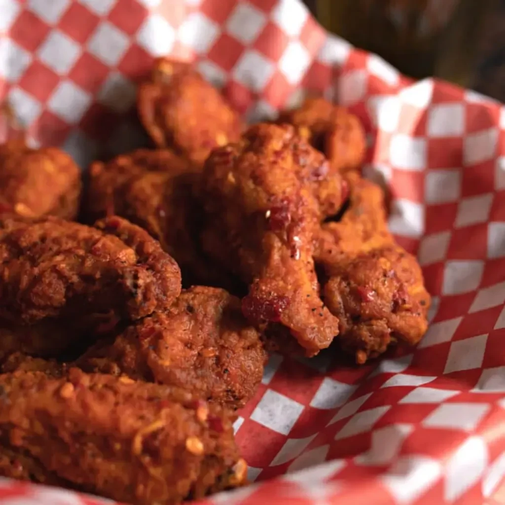 Crispy, reddish-orange seasoned chicken wings in a checkered basket.
