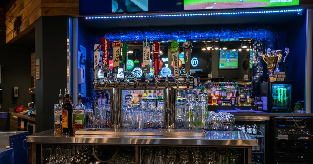 Beer taps, liquor, and TVs showing baseball in a modern bar.