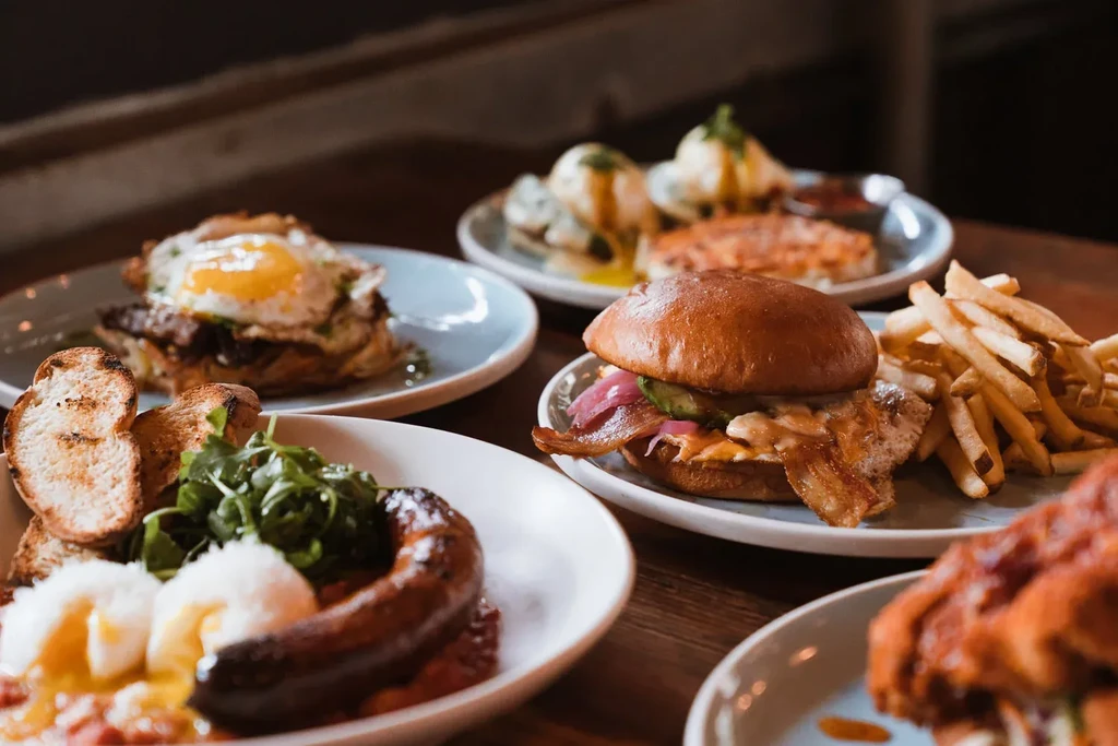 Various food dishes including sausage, eggs, a burger, and fries.