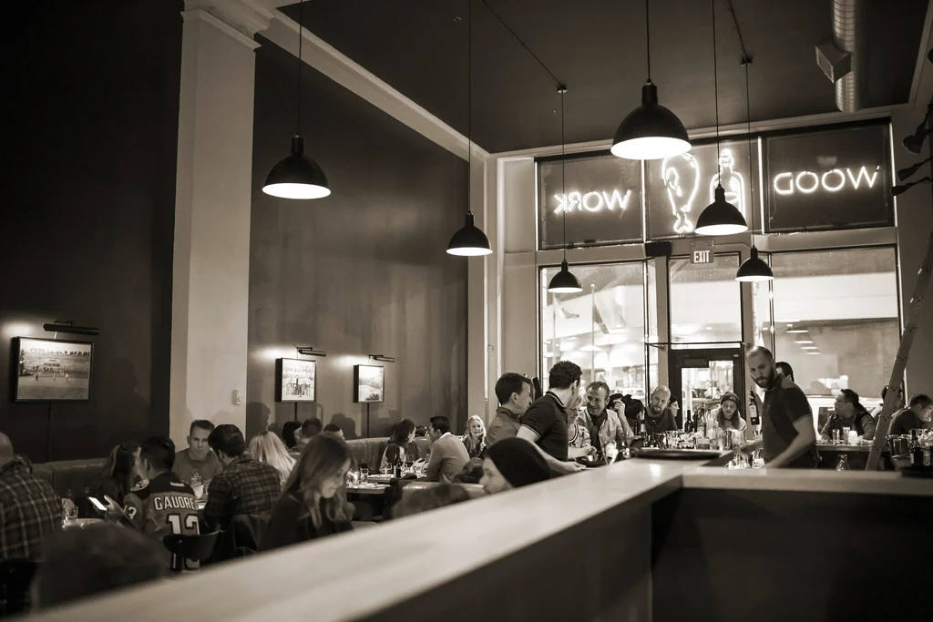 Black and white image of a lively, modern bar with patrons.