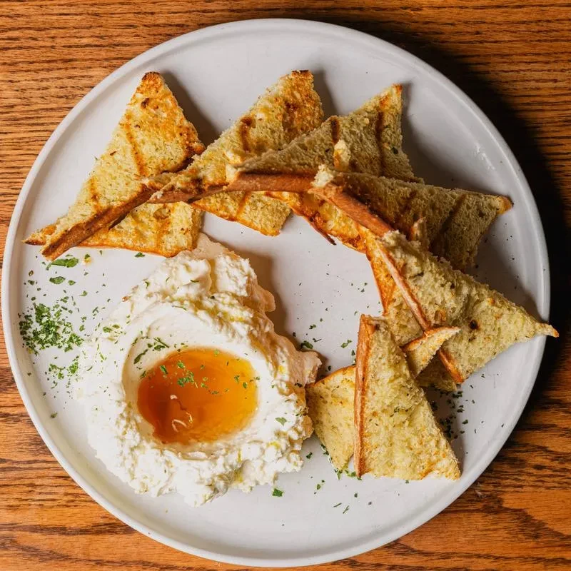 Silky cheese with amber liquid, herbs, and grilled bread.