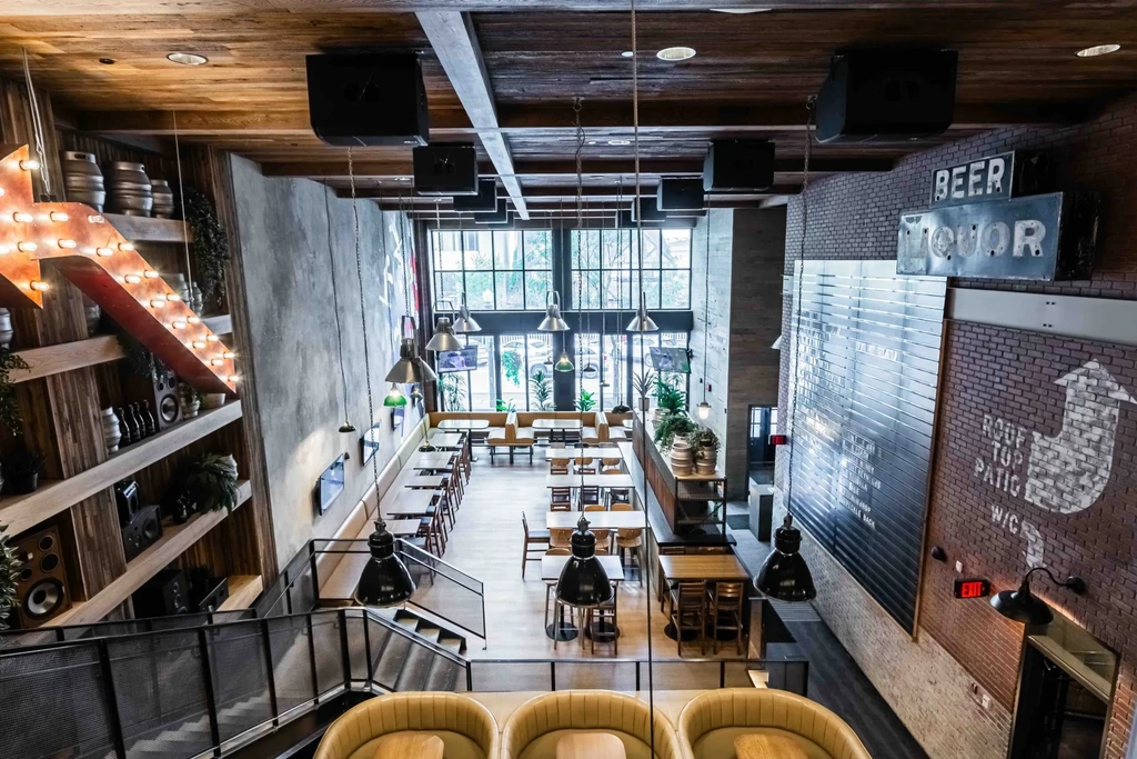 Multi-level modern industrial restaurant interior with various seating and signs.