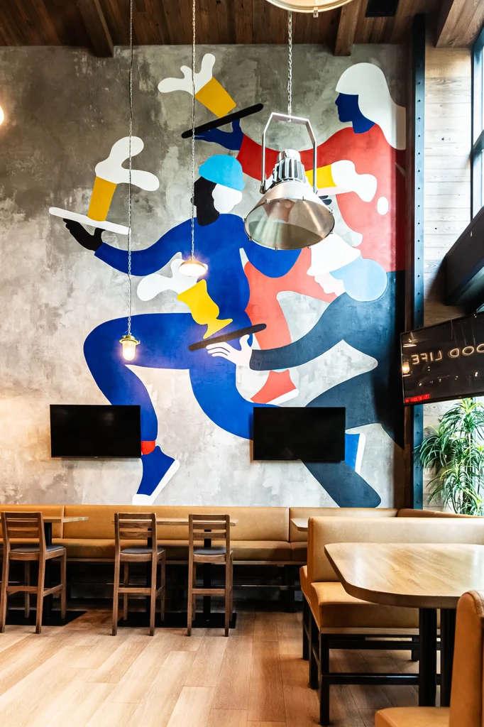 Colorful abstract mural in a modern restaurant with booths and pendant lights.