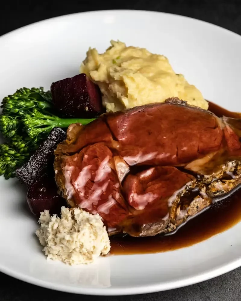 Plated roasted prime rib, mashed potatoes, broccolini, beets, and horseradish.