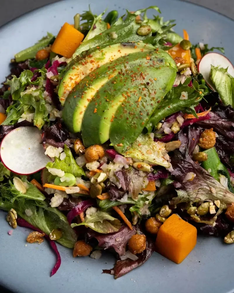 Close-up of a vibrant mixed green salad with avocado and chickpeas.