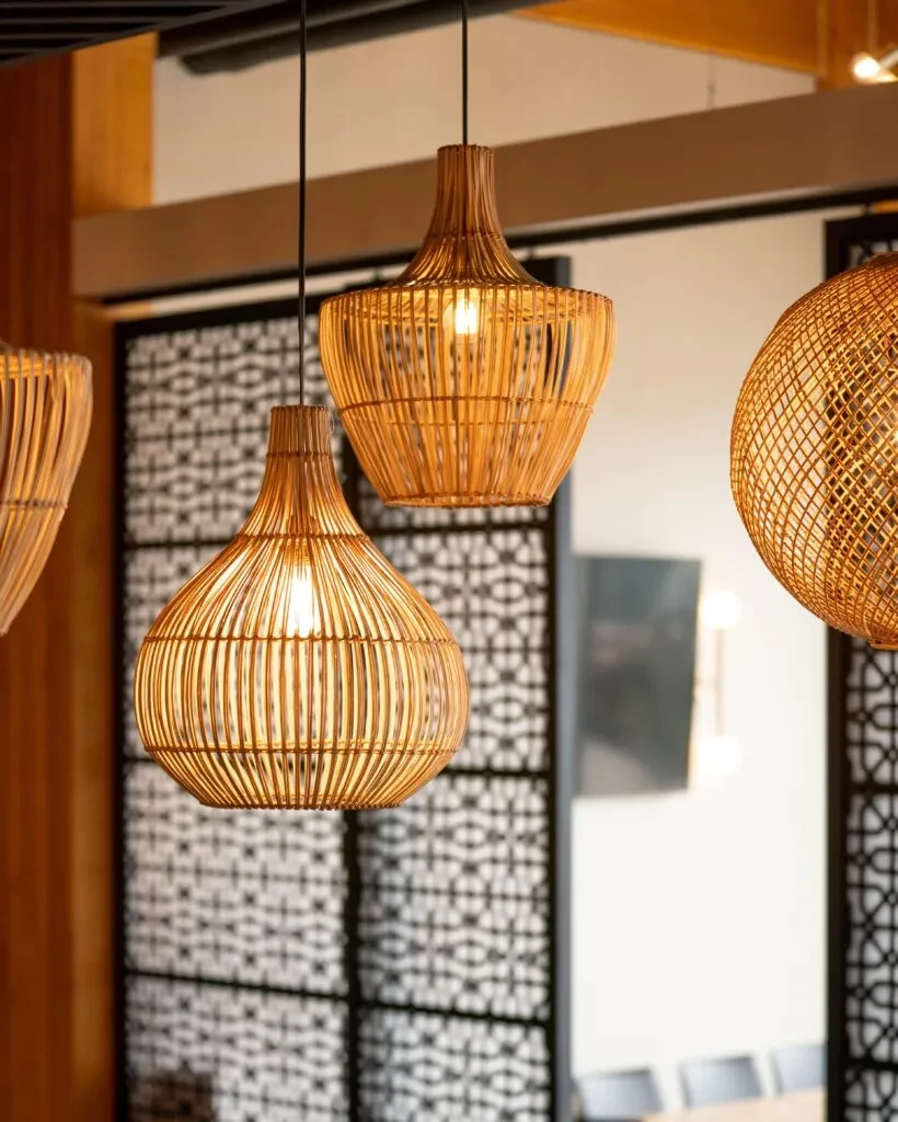 Three woven rattan pendant lights glow warmly in a cafe.