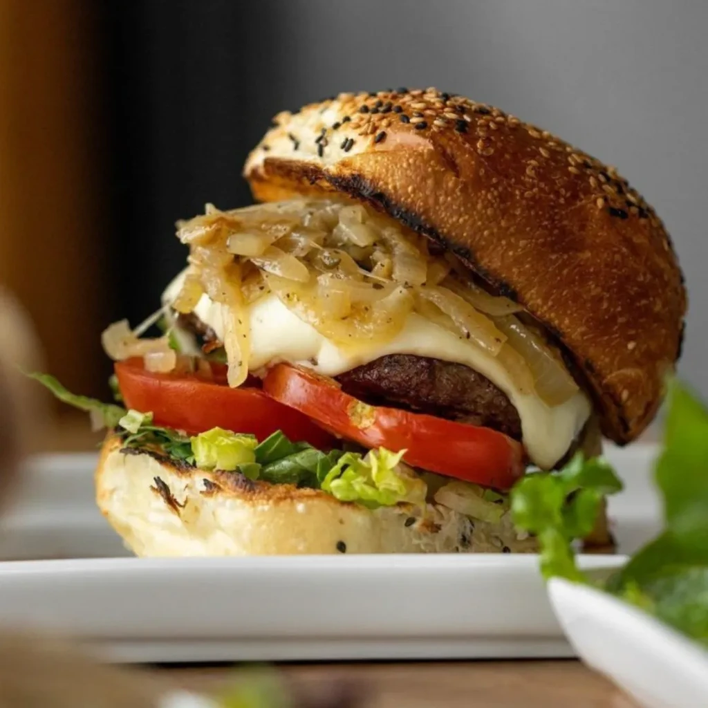 Gourmet beef burger with melted cheese, caramelized onions, tomato, and lettuce.