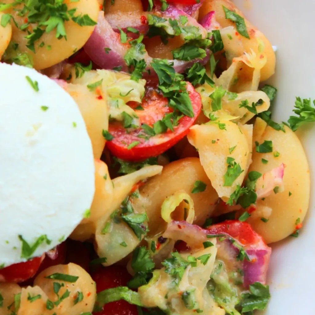 Colorful potato, tomato, and onion salad with burrata and creamy dressing.