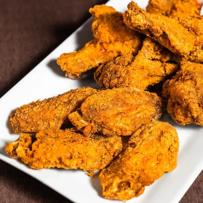 Crispy golden-brown fried chicken pieces piled on a white plate.