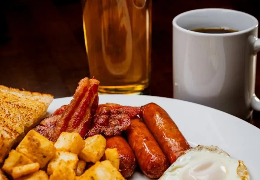 Breakfast plate with egg, bacon, sausage, home fries, and toast.