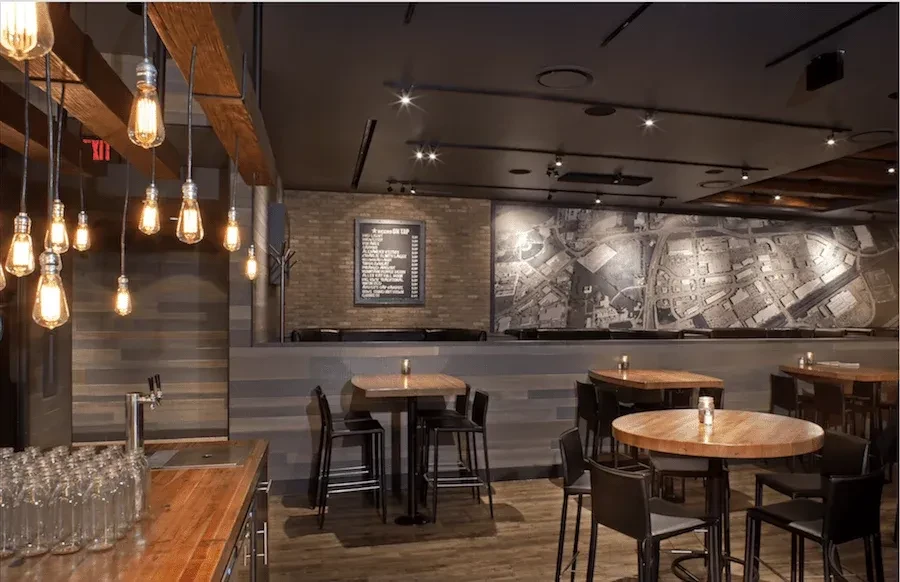 Industrial-chic restaurant interior with wood bar, exposed brick, and map mural.