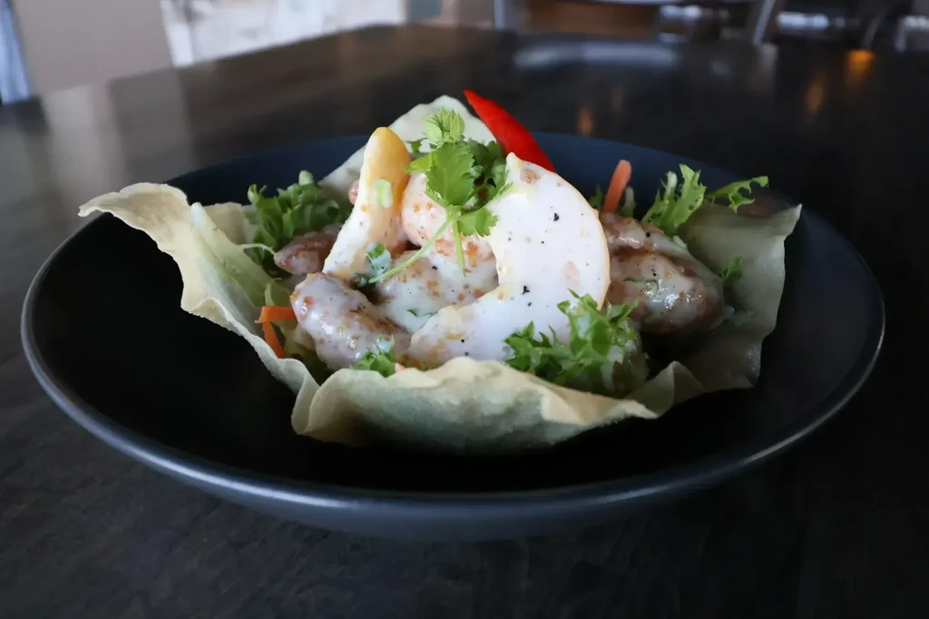 Shrimp appetizer with lettuce, carrots, and cilantro in a crispy wrapper.
